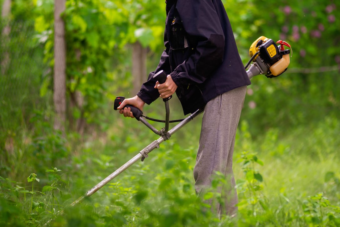 Caucasian Gardener working man Manual hand grass cutter  Weed Cutter or Power Weeder or Brush Cutter Lawn Mowe  Gasoline close up.